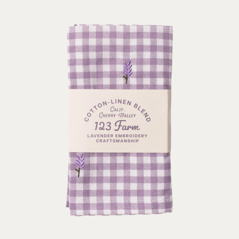 Purple gingham fabric with embroidered lavender and text on a white background